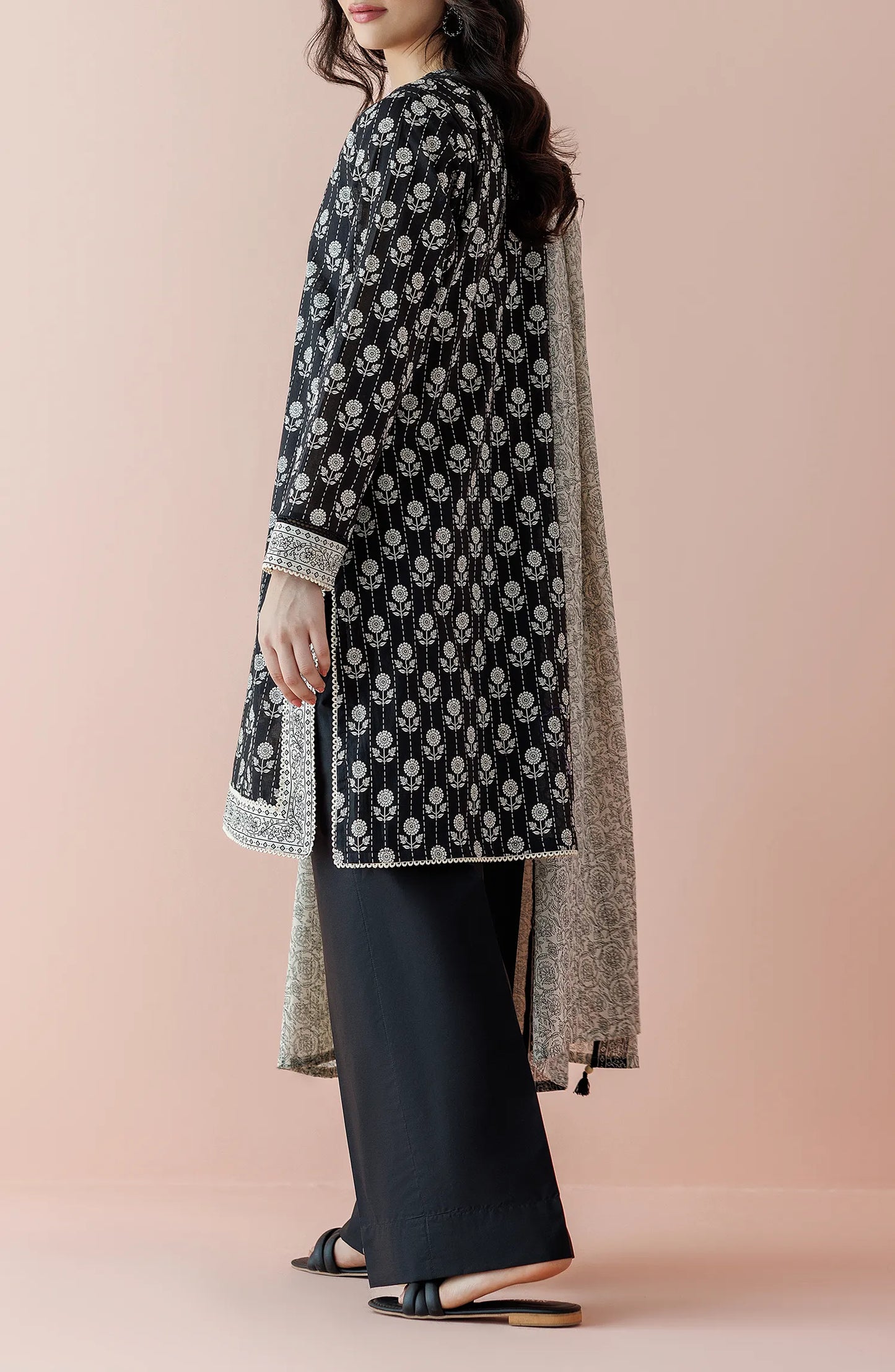 Woman wearing a black floral kurta with black pants and a light gray dupatta on a plain black trouser. Unstitched Printed Lawn Shirt Dupatta & Pant - 3 Piece Suits - OTL-20025