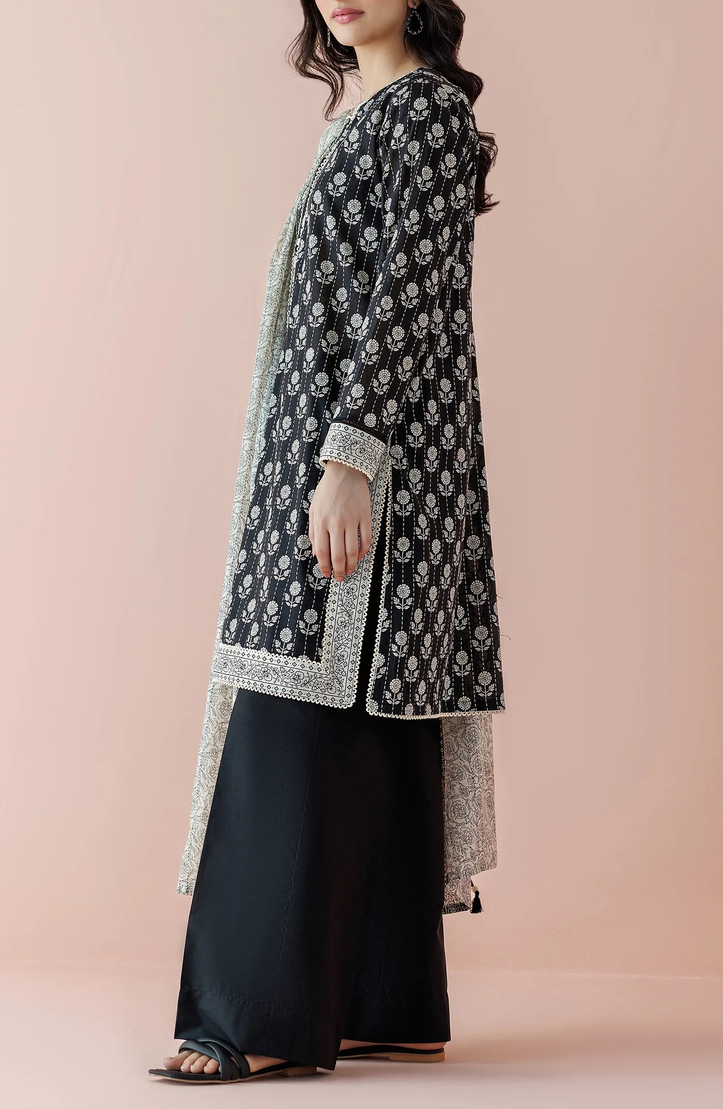 Woman wearing a black floral kurta with black pants and a light gray dupatta on a plain black trouser. Unstitched Printed Lawn Shirt Dupatta & Pant - 3 Piece Suits - OTL-20025