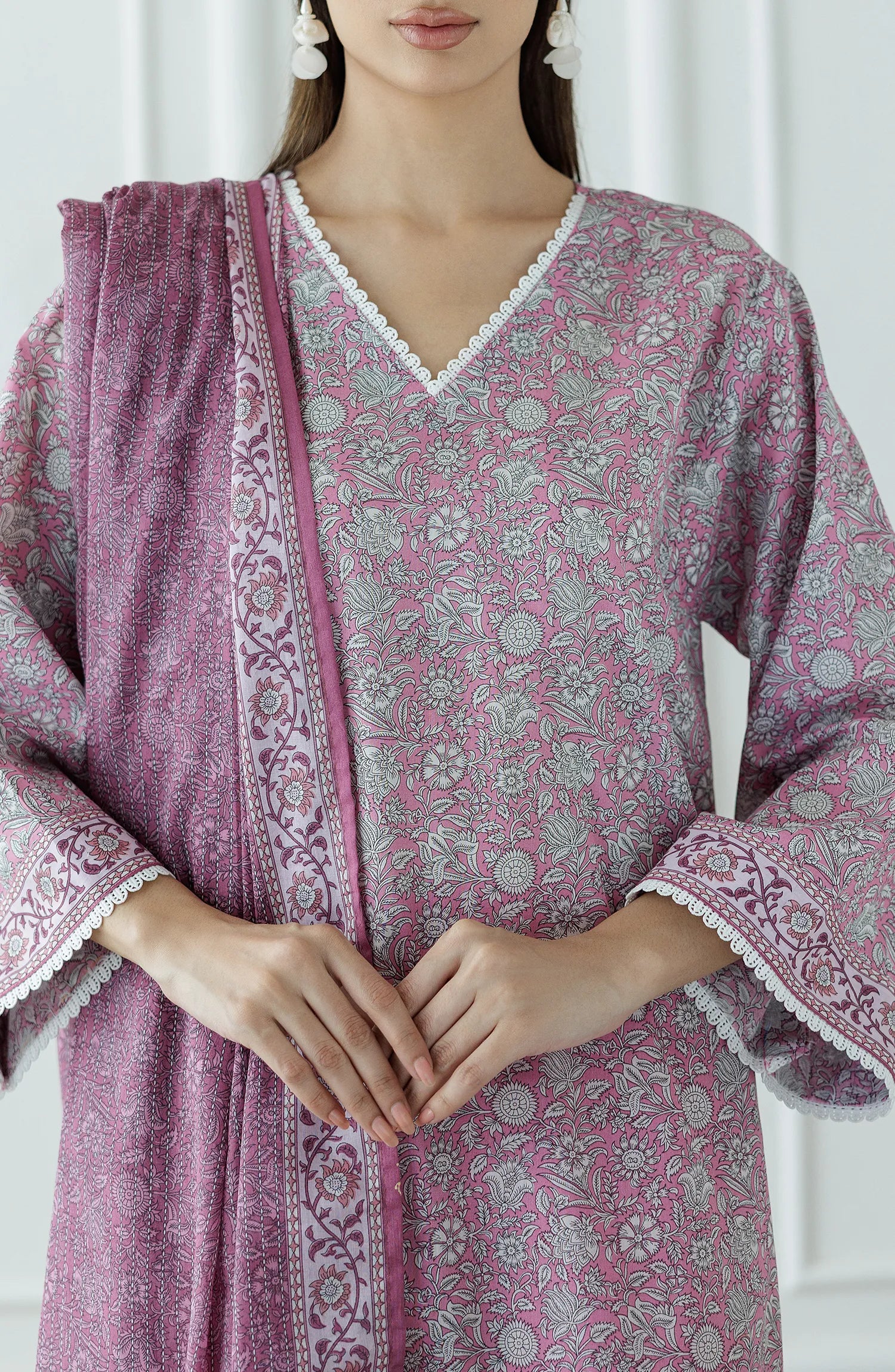 Woman wearing a pink traditional outfit with a matching dupatta against a matching traditional shalwar. Stitched Printed Lawn Shirt Dupatta & Pant - 3 Piece - OTL-25-309.