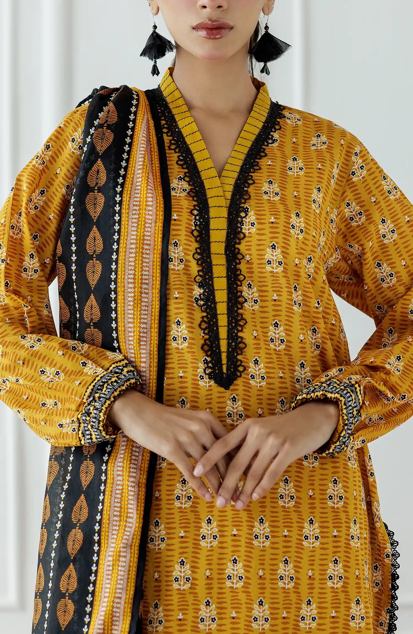 Stitched Printed Lawn Shirt Dupatta & Pant - 3 Piece - OTL-25-310. Woman wearing a yellow traditional outfit with a black and gold dupatta against a white background