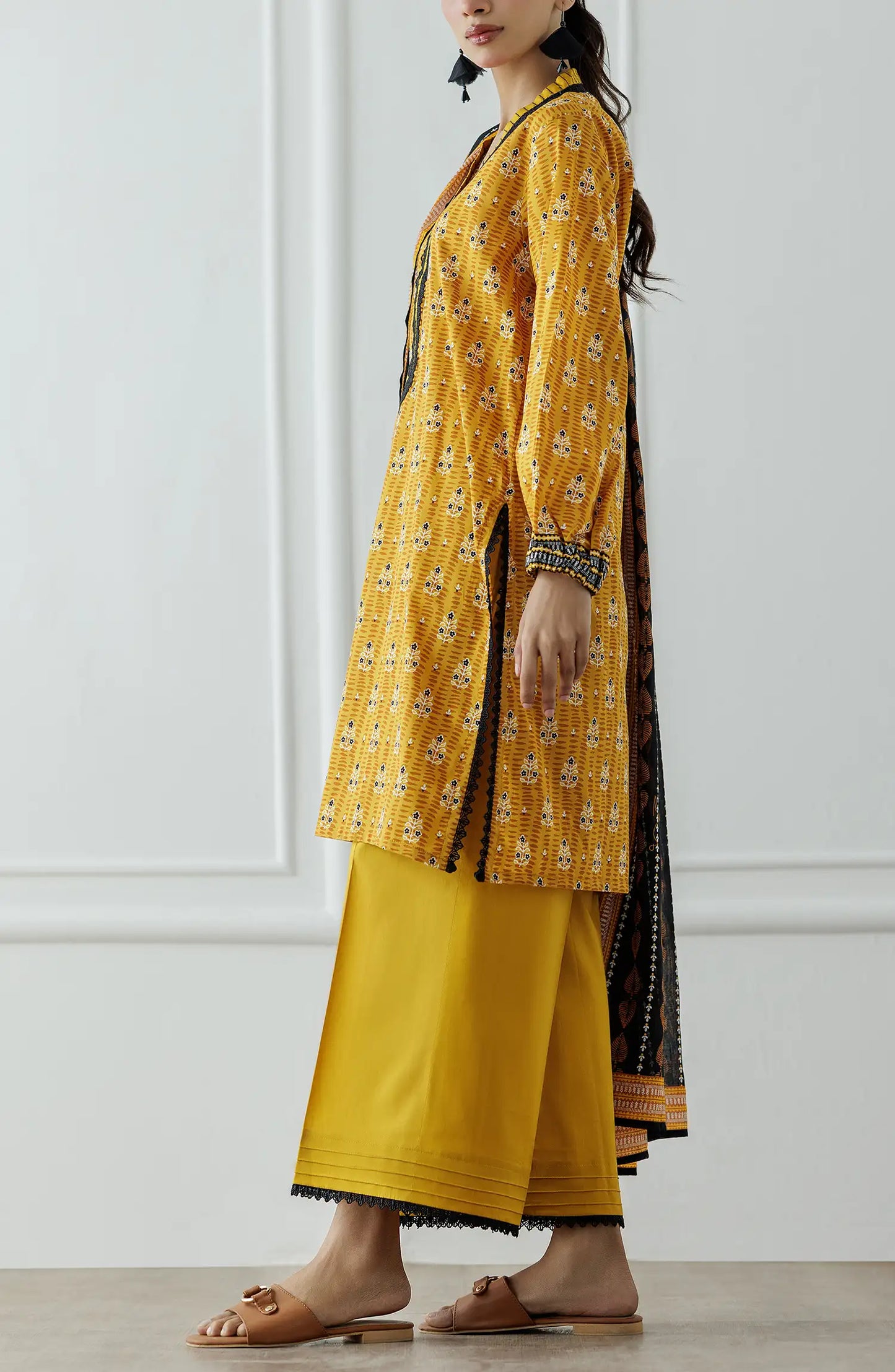 Stitched Printed Lawn Shirt Dupatta & Pant - 3 Piece - OTL-25-310. Woman wearing a yellow traditional outfit with a black and gold dupatta against a white background