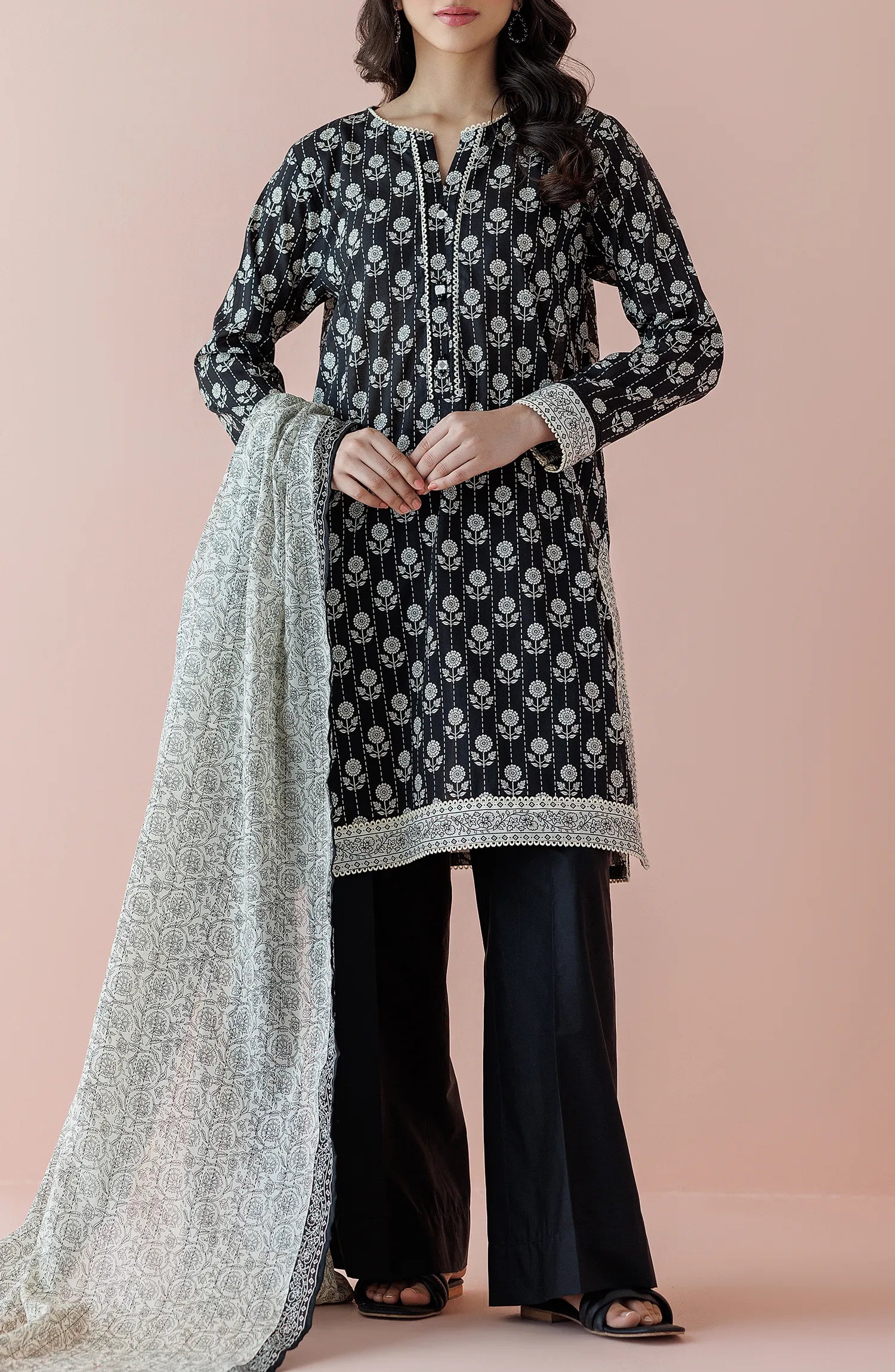 Woman wearing a black floral kurta with black pants and a light gray dupatta on a plain black trouser. Unstitched Printed Lawn Shirt Dupatta & Pant - 3 Piece Suits - OTL-20025