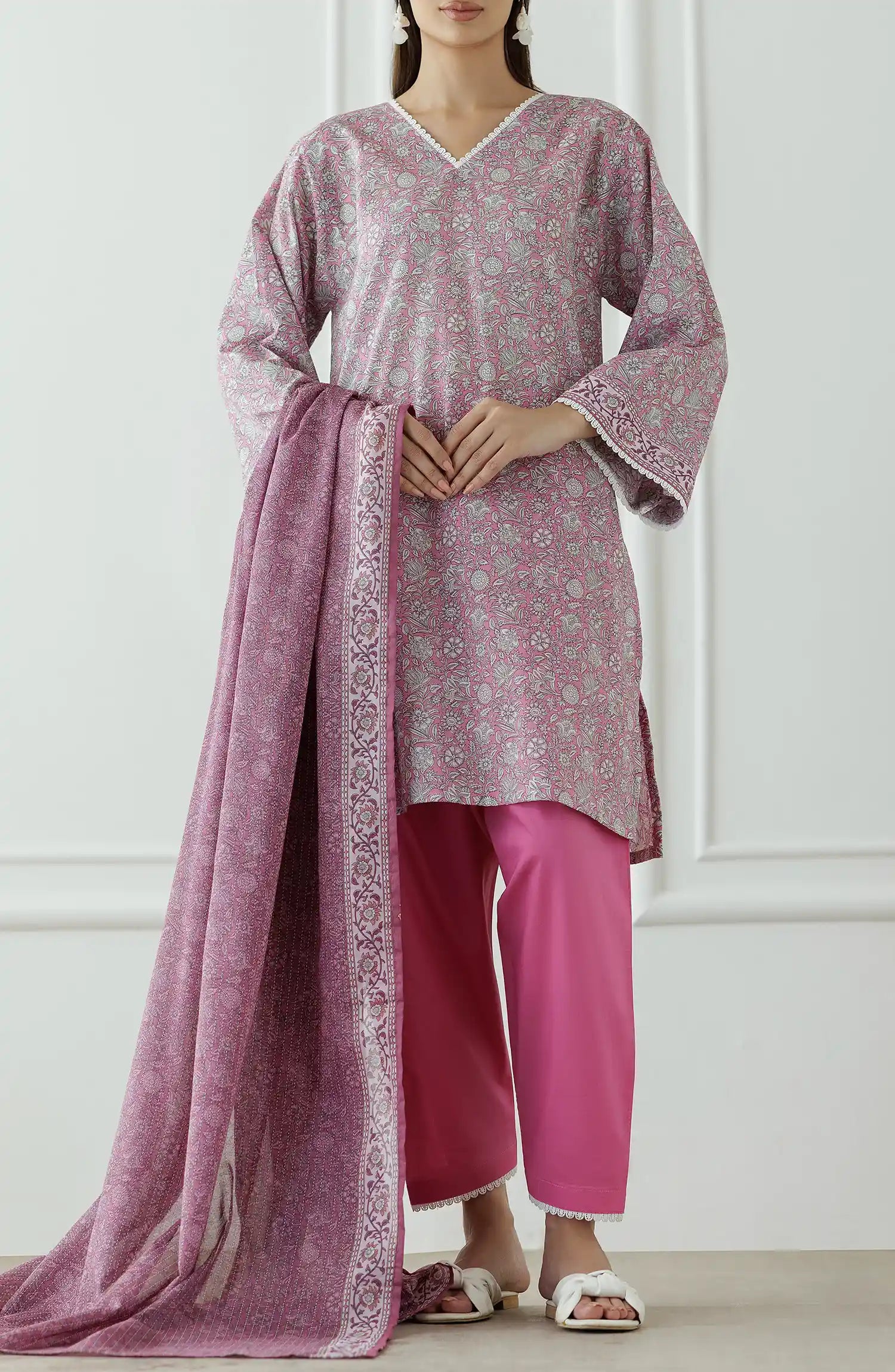 Woman wearing a pink traditional outfit with a matching dupatta against a matching traditional shalwar. Stitched Printed Lawn Shirt Dupatta & Pant - 3 Piece - OTL-25-309. 