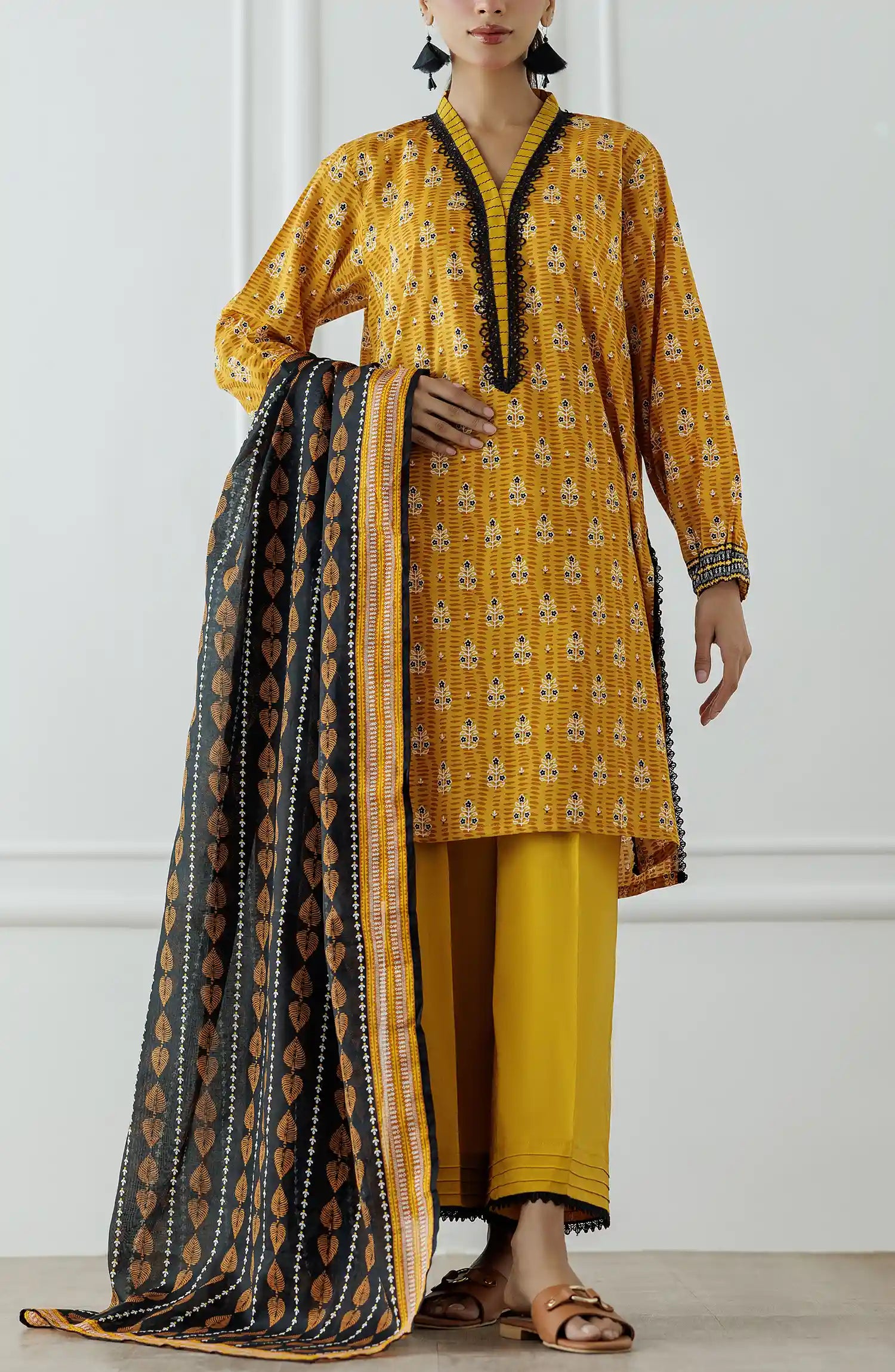 Stitched Printed Lawn Shirt Dupatta & Pant - 3 Piece - OTL-25-310. Woman wearing a yellow traditional outfit with a black and gold dupatta against a white background