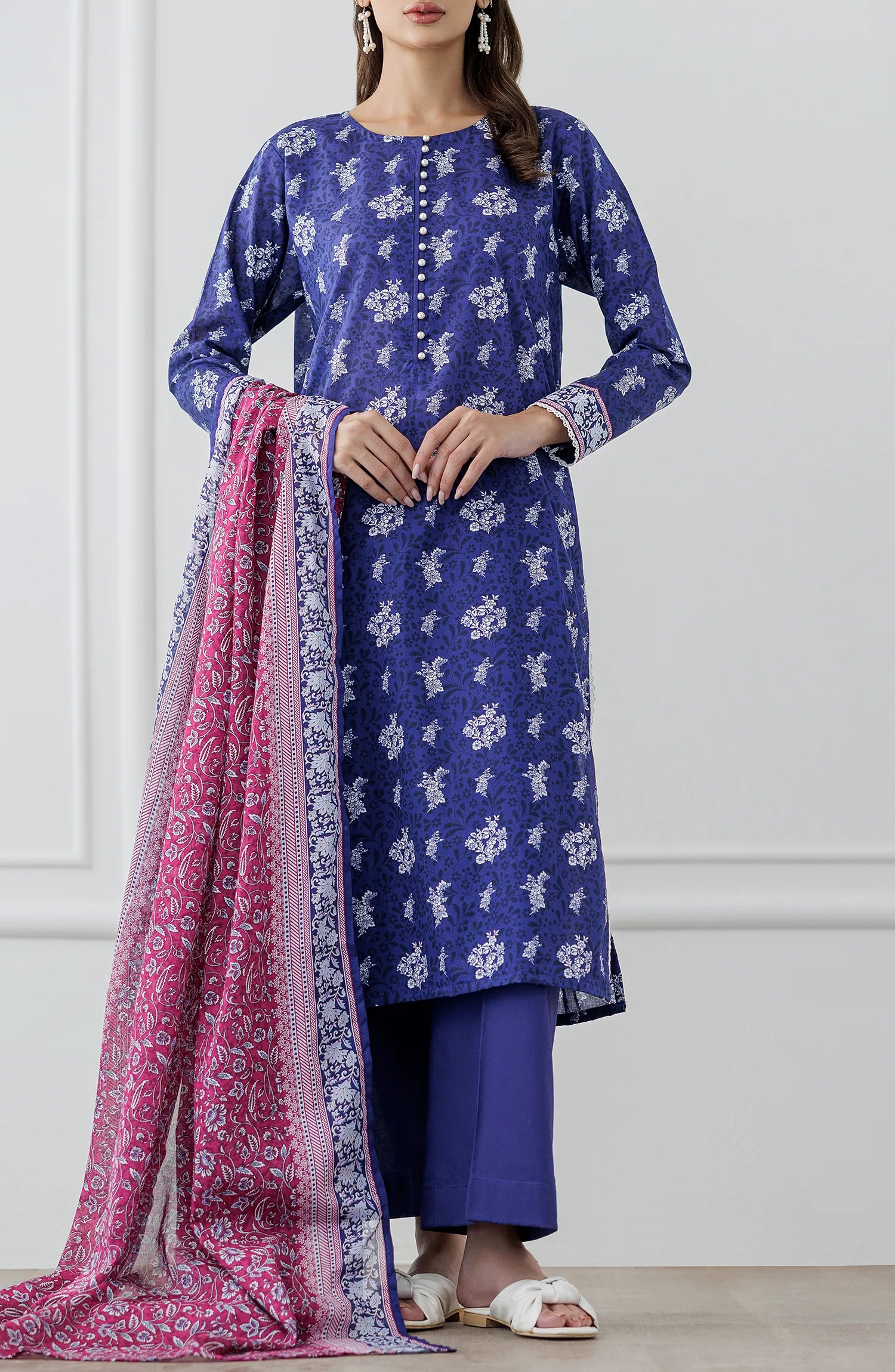 Woman wearing a blue floral dress with a pink dupatta against a dyed trouser. Unstitched Printed Lawn Shirt Dupatta & Pant - 3 Piece Suits - OTL-25-476